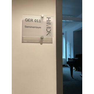 T&uuml;rschild Seminarraum GER011 HfMDK Frankfurt a.M., ge&ouml;ffnete T&uuml;r mit Sicht auf Fl&uuml;gel; 14.11.2025<br>(Foto: Alexandra Klein)