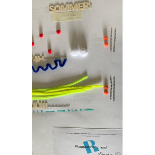 Nahansicht taktile Komposition aus Holzbuchstaben, Chenilledraht, Ponpons, Brailleschrift, 3D Paste, Silberpunkte; Komposition Sommer der Klasse 5e auf weißer Pappe; Gymnasium Wendalinum WND (4): 11.06.2025<br>(Foto: Alexandra Klein)